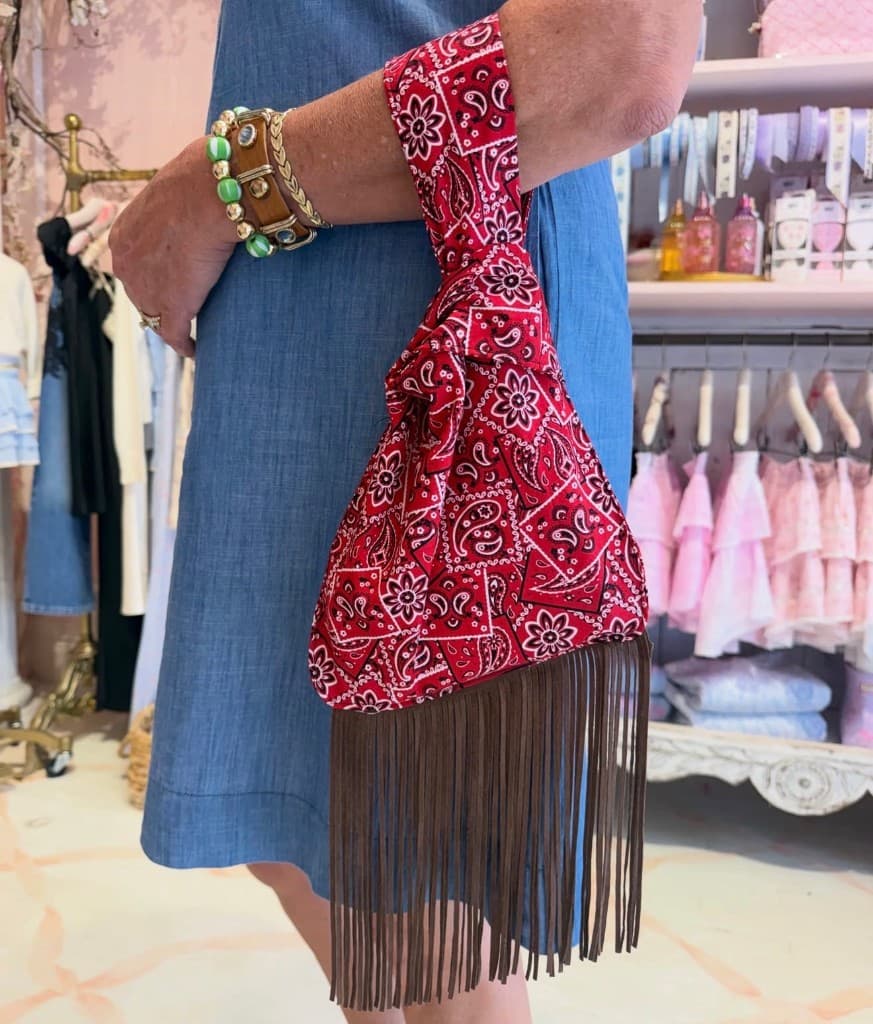 Red bandana knot bag with brown fringe worn on the wrist